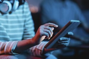 vista-lateral-de-uma-mulher-em-casa-usando-fones-de-ouvido-e-tablet